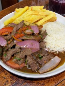 Lomo saltado peruano con patatas fritas, arroz blanco y verduras salteadas