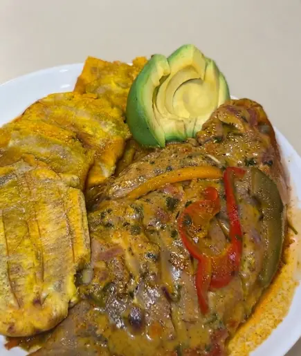 Pescado con coco dominicano guisado en salsa, servido con tostones crujientes y aguacate