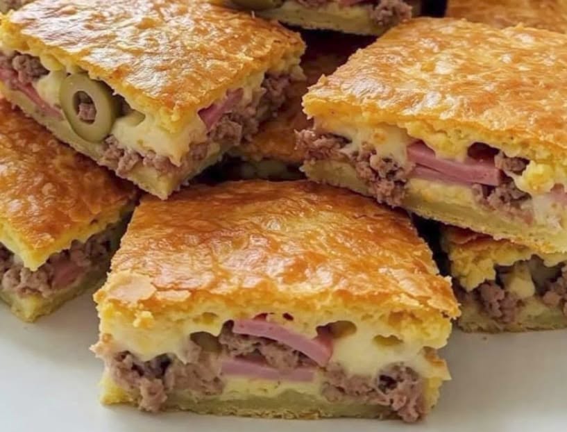Porciones de empanada de hojaldre rellena de pollo, jamón york, queso y aceitunas