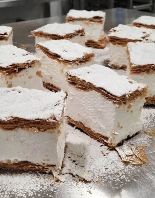Porciones de milhojas de hojaldre rellenas de merengue y cubiertas de azúcar glas