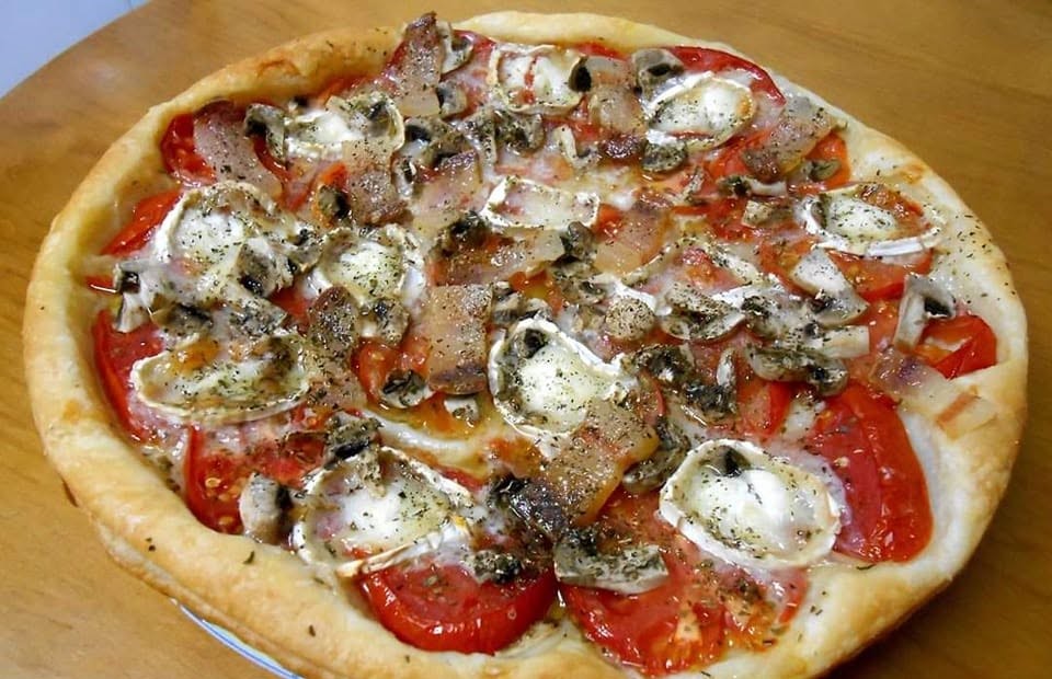 Pizza de hojaldre redonda con tomate natural, champiñones, panceta y rulo de queso de cabra